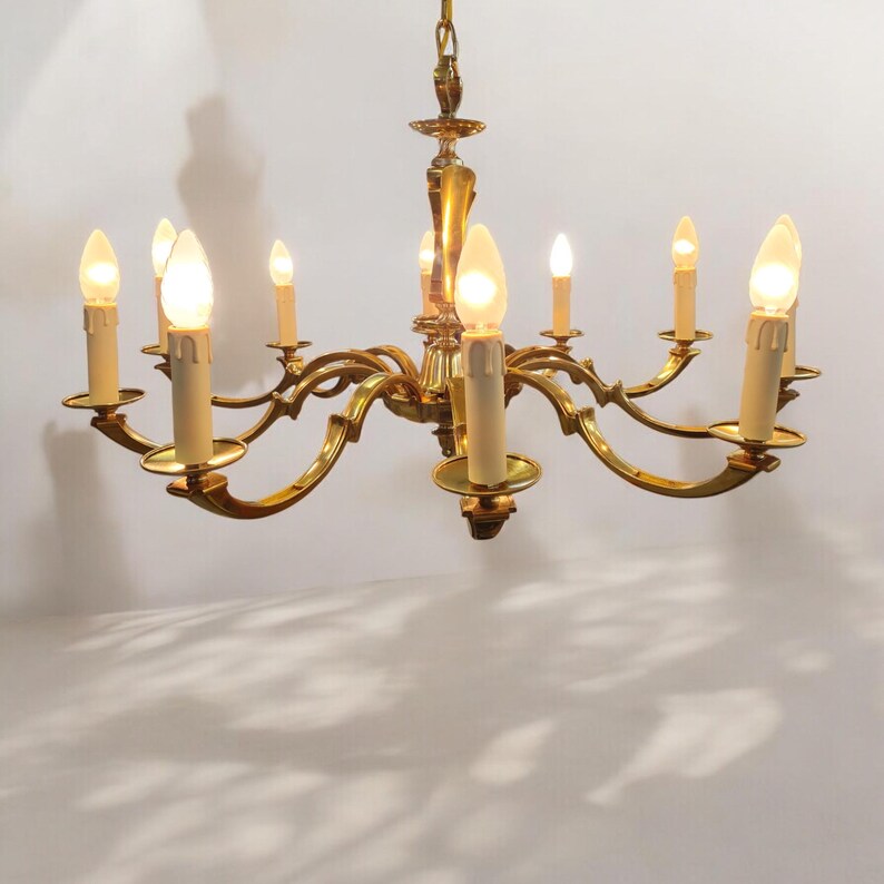 May include: A gold-toned brass chandelier with eight candle-style light bulbs. The chandelier has a traditional design with curved arms and a central decorative element.