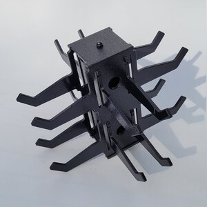 May include: Black metal display stand with multiple arms extending out from a central square base. The stand is designed to hold items like jewelry or small accessories.