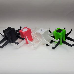 May include: Four colorful, star-shaped, plastic stands with legs. The stands are black, red, white, and green.