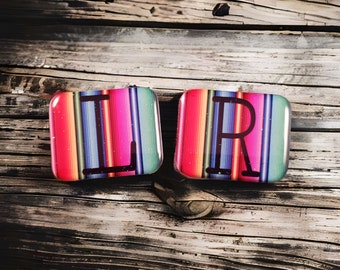 May include: Two colorful square tiles with the letters "L" and "R" in black on a wood background. The tiles have a striped pattern in shades of pink, red, blue, green, and yellow.