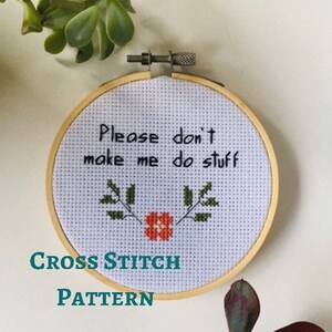 May include: Cross stitch pattern with the text "Please don't make me do stuff" in black lettering, a red flower, and green leaves on a white background.