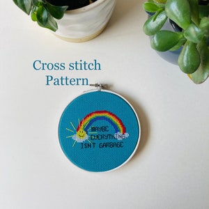 May include: Cross stitch pattern featuring a rainbow, sun, and the text "Maybe everything isn't garbage".