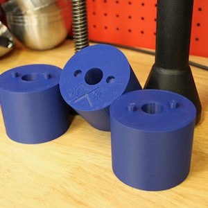 May include: Three blue plastic cylindrical spacers with a hole in the center. The spacer on the left has no markings. The spacer in the center has the text "X" and "XI" on it. The spacer on the right has no markings.