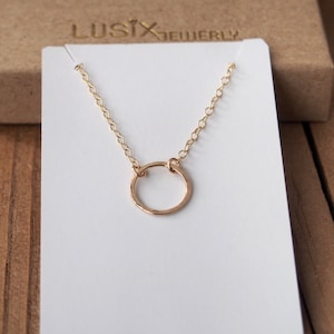 K&ouml;nnte beinhalten: Eine zarte goldene Halskette mit einem geh&auml;mmerten Kreisanh&auml;nger. Die Halskette liegt auf einer wei&szlig;en Karte mit dem Text "Lusix Jewelry".