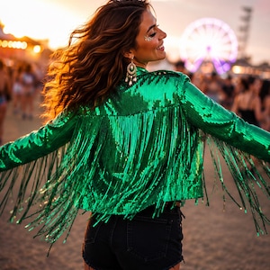 May include: A vibrant emerald green jacket covered in shimmering sequins, featuring long, flowing fringe detailing along the back and sleeves, paired with dark denim shorts. The jacket has a structured collar and a cropped fit with a full fringe trim.