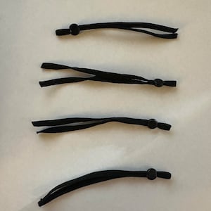 May include: Four black elastic straps with adjustable toggles. The toggles are black plastic and round.