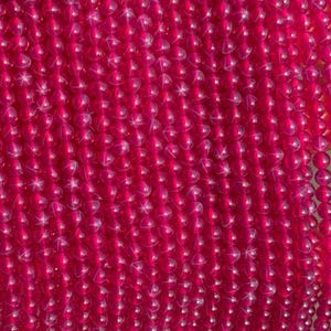 Op de afbeelding: Close-up van een verzameling levendige, doorschijnende, fuchsia-kleurige kralen. De kralen zijn rond en lijken aan elkaar geregen te zijn, waardoor een dicht, gestructureerd oppervlak ontstaat. Het licht reflecteert op de kralen, waardoor highlights en een sprankelend effect ontstaan.