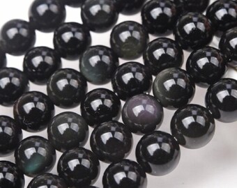 May include: A close-up of a strand of black obsidian gemstone beads. The beads are round, polished, and have a glossy sheen. Some beads have subtle iridescent color variations.