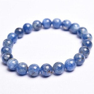 May include: A beaded bracelet featuring round, polished blue gemstones. The beads are strung together to form a circular shape. The gemstones have a mix of light and dark blue hues, with some showing subtle variations in color and texture. The bracelet is set against a white background.