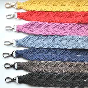 May include: Seven colorful macrame keychains with heart-shaped designs. The keychains are in the colors yellow, red, pink, blue, navy blue, brown, and black.