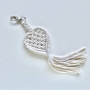 May include: White macrame heart keychain with a silver key ring and a long tassel.