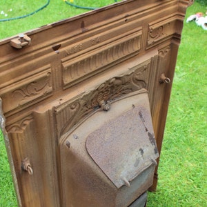 Pu&ograve; includere: Un camino in ghisa vintage con dettagli intricati e un design decorativo. Il camino &egrave; di colore marrone ruggine e ha il numero "N189 122" inciso sulla parte superiore.