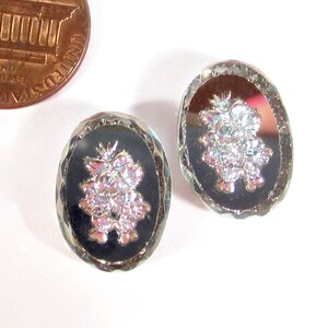 May include: A pair of silver tone earrings with a black background and a silver grape design.