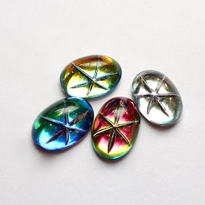 May include: Four iridescent oval-shaped glass stones with a star design in the center. The stones are in shades of blue, green, red, and silver.