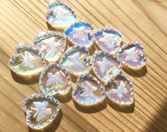 May include: A group of iridescent heart-shaped glass charms with a white butterfly design. The charms have a scalloped edge and are perfect for adding a touch of sparkle to any craft project.