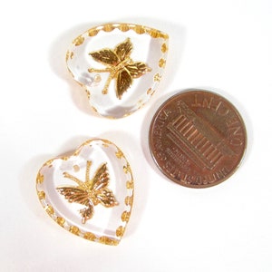 Puede incluir: Tres colgantes transparentes en forma de coraz&oacute;n con dise&ntilde;os de mariposas doradas y adornos dorados. Se incluye una moneda para comparar el tama&ntilde;o. Los colgantes tienen un peque&ntilde;o agujero en la parte superior para ensartar.