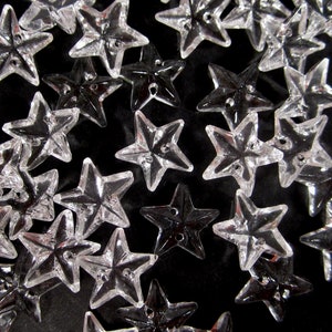 May include: A collection of clear and black star-shaped buttons. The buttons are made of plastic and have a shiny finish.