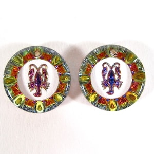 May include: A pair of round, iridescent earrings with a lobster design in the center. The earrings have a multi-colored, mosaic-like pattern around the edge.