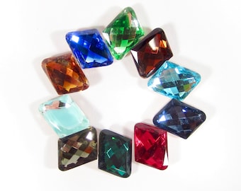 May include: A collection of ten faceted, diamond-shaped rhinestones in various colors, including red, green, blue, brown, and turquoise. The rhinestones are arranged in a circle on a white background.