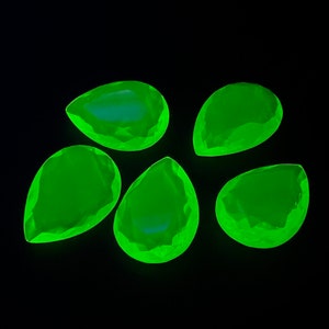 Könnte beinhalten: Fünf tropfenförmige grüne Glassteine mit facettierter Oberfläche.
