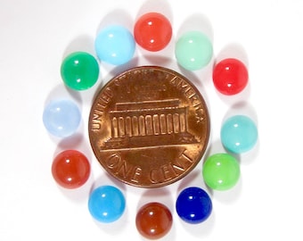 May include: A circle of 10 small, round, colourful glass beads arranged around a US penny. The beads are in various colours, including red, green, blue, and turquoise.