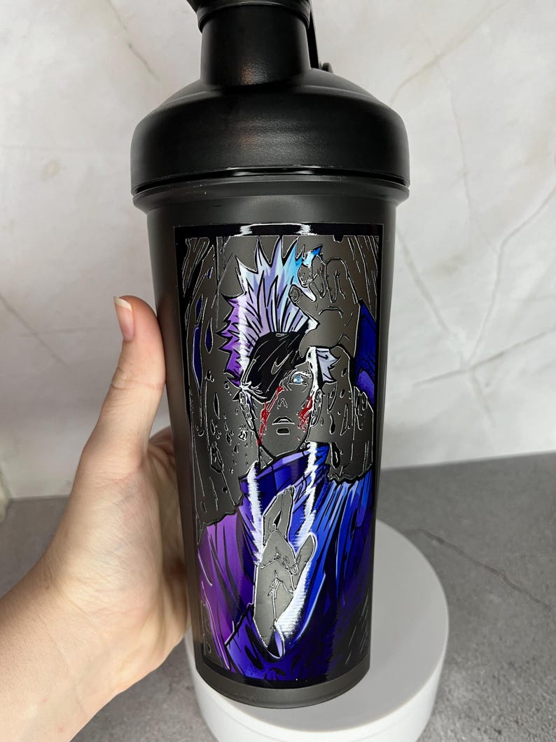 May include: Black shaker bottle with a graphic of an anime character with white hair and a purple and blue outfit. The character is surrounded by a black and white background.