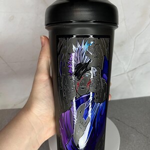 May include: Black shaker bottle with a graphic of a character from the anime Naruto. The character has white hair, blue eyes, and is wearing a purple and blue outfit. The background is black and white.
