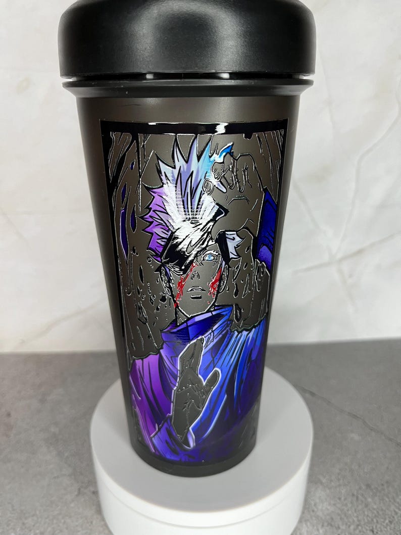 May include: Black shaker bottle with a graphic of a character with white hair and a purple and blue outfit. The character has a red mark on their face.