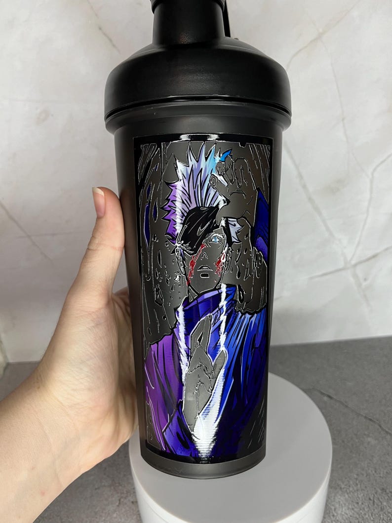 May include: Black shaker bottle with a graphic of a character with white hair and a purple and blue outfit. The character has a red mark on their face.