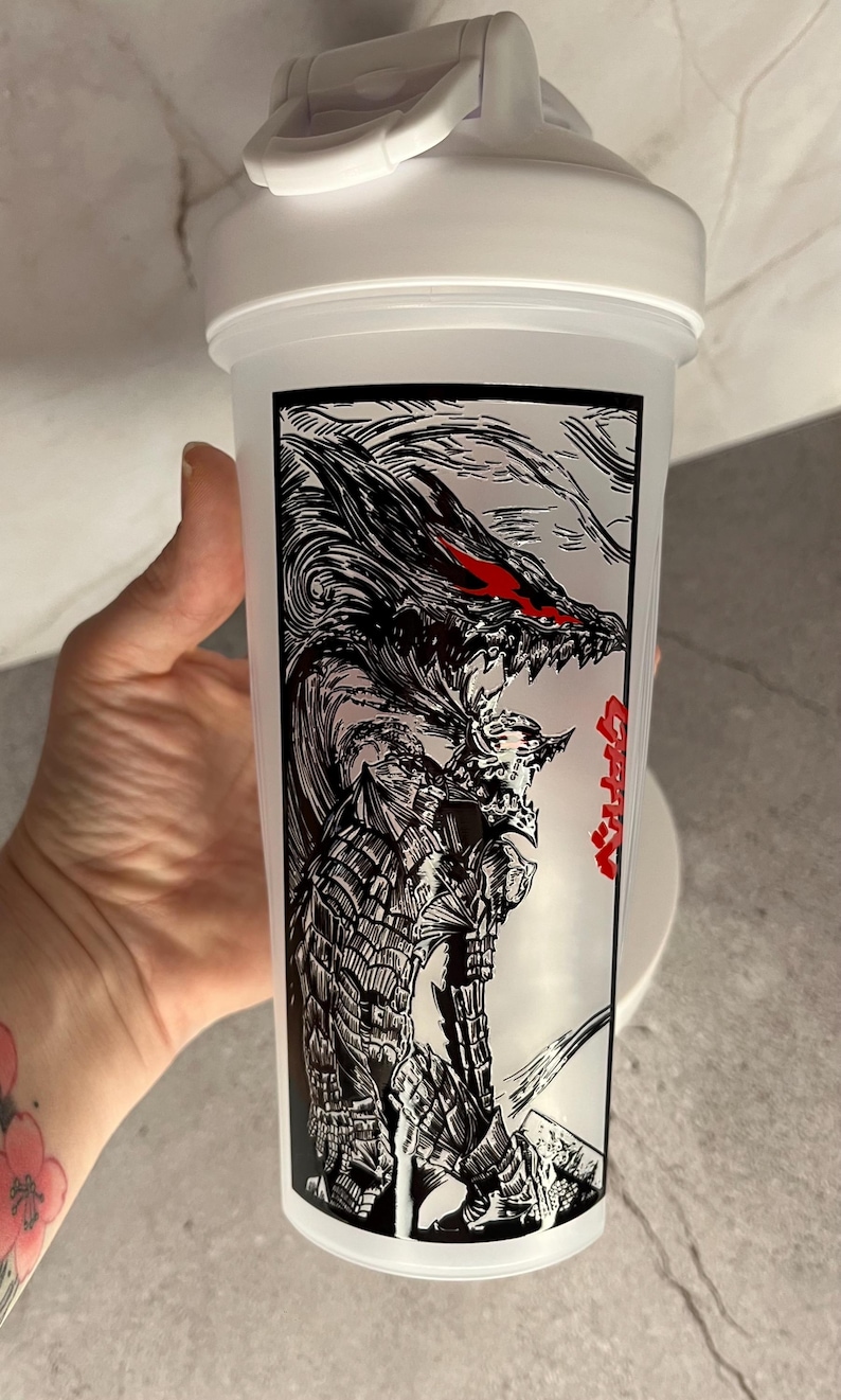 May include: White plastic shaker bottle with a black and red graphic of a dragon-like creature. The design features intricate details and the text in Japanese. The bottle has a white lid with a handle.