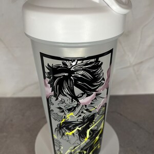 May include: White shaker bottle featuring a black and white graphic of an anime character with lightning bolts. The character has a fierce expression and is surrounded by smoke.