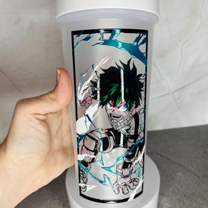 May include: White shaker bottle with a green and black anime character graphic. The character is surrounded by white and blue lightning bolts.
