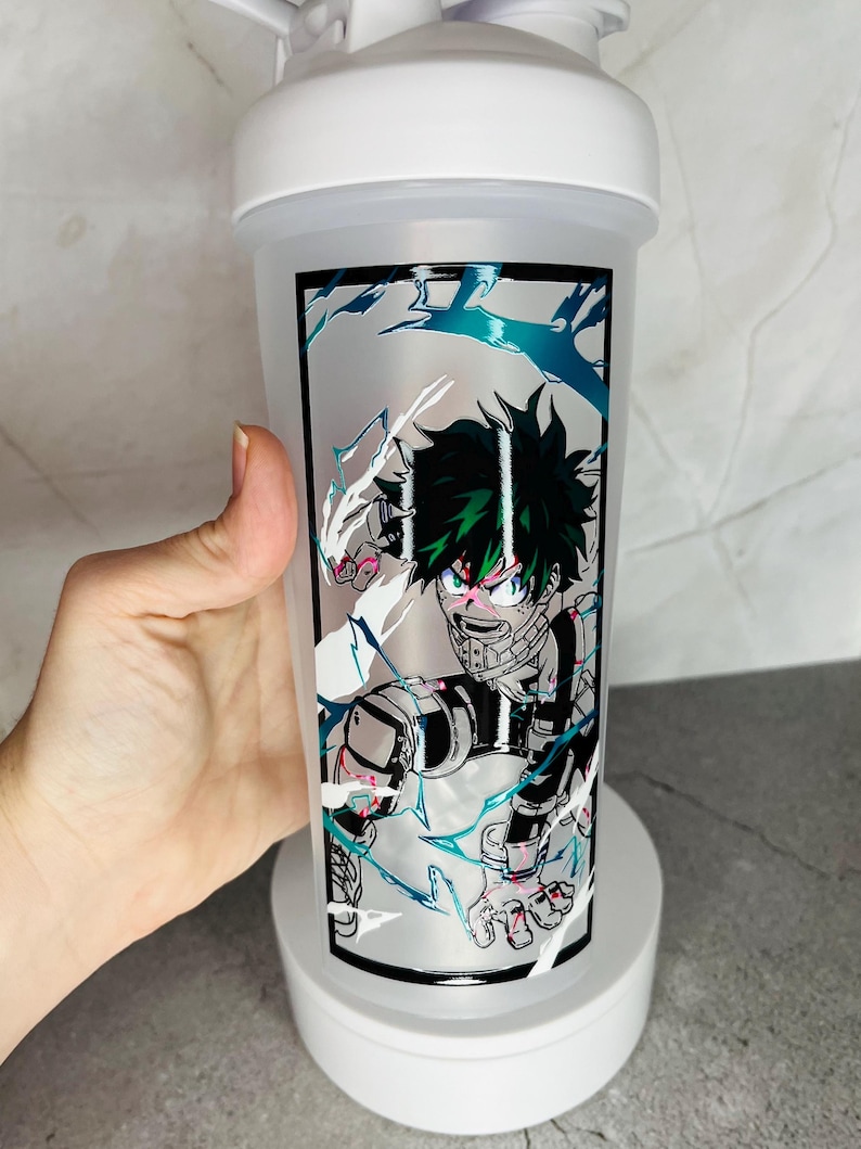 May include: White shaker bottle with a green and black anime character graphic. The character is surrounded by white and blue lightning bolts.