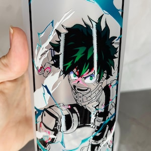 May include: A white tumbler with a green, black, and white anime character design. The character is surrounded by white and blue lightning bolts.