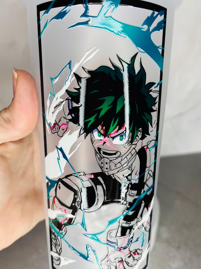 May include: A white tumbler with a green, black, and white anime character design. The character is surrounded by white and blue lightning bolts.