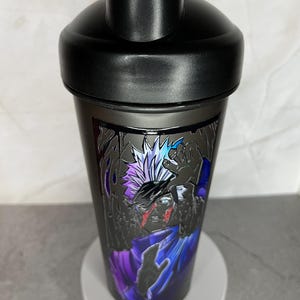 May include: Black shaker bottle with a graphic of a character with white hair and a purple and blue outfit. The character has a red scar on their face.