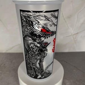 May include: A white and clear plastic shaker bottle featuring a black and white illustration of a monster with red eyes and teeth. The bottle has a white lid and is on a white stand.