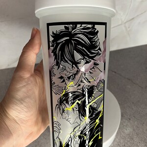 May include: White shaker bottle featuring a black and white graphic of anime characters. The characters are surrounded by yellow lightning bolts.