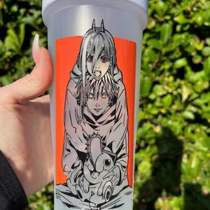 Pu&ograve; includere: Una bottiglia shaker in plastica trasparente con coperchio bianco. La bottiglia presenta un vivace adesivo rettangolare arancione con un'illustrazione in bianco e nero in stile anime di due personaggi. Un personaggio ha gli occhi rossi e l'altro gli occhi gialli.