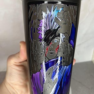 May include: Black shaker bottle with a graphic of a character from an anime or manga. The character has white hair and is wearing a blue and purple outfit. The graphic is in a silver metallic style.