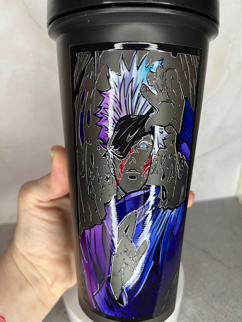 May include: Black shaker bottle with a graphic of a character from an anime or manga. The character has white hair and is wearing a blue and purple outfit. The graphic is in a silver metallic style.