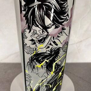 May include: A white tumbler featuring a black and white graphic of three anime characters. The characters are drawn in a manga style and have black hair and eyes. The background is a black and white pattern of lightning bolts.