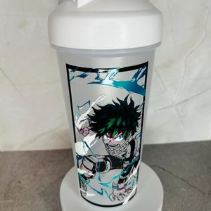 May include: White shaker bottle with a green and black anime character design. The character is surrounded by white and blue lightning bolts. The bottle has a white lid with a black spout.