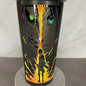 May include: Black shaker bottle with a graphic of a character from the anime Attack on Titan. The character is surrounded by flames and has green eyes.