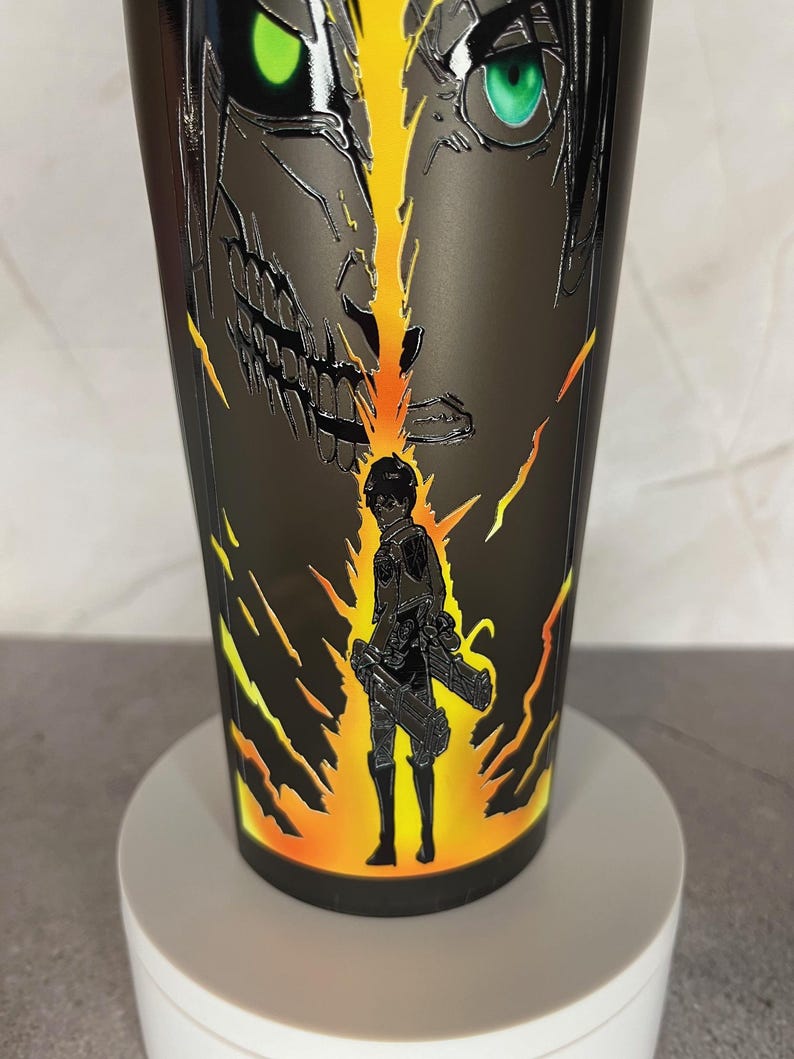 May include: Black and yellow tumbler with a graphic of a character from the anime Attack on Titan. The character is shown in both human and titan form.