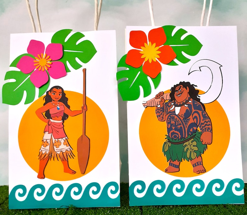 May include: Two colorful gift bags with images of Moana and Maui from the Disney movie Moana. The bags feature a tropical theme with green leaves, flowers, and ocean waves.
