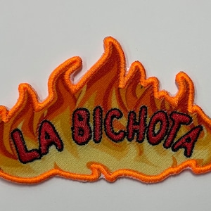 May include: Orange and yellow embroidered patch with the text "LA BICHOTA" in red.