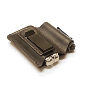 Puede incluir: Una funda de cuero marrón para herramientas múltiples con un clip de metal y una herramienta múltiple plateada en el interior.