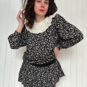 Peut inclure: Une robe à fleurs noires et blanches avec un col en dentelle blanche et une jupe à volants.