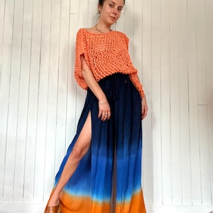 May include: An orange crochet top paired with navy blue and ombre blue-orange palazzo pants. The pants have a high slit on the side. The outfit is worn with wooden clogs.